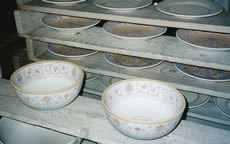 Hand-painted Italian pottery drying on racks.
